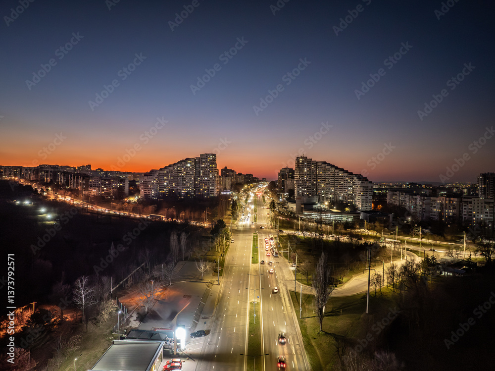 Drone view of the Chisinau Gates, the city symbol, above the busy Dacia Boulevard with cars at sunset and building lights in the evening