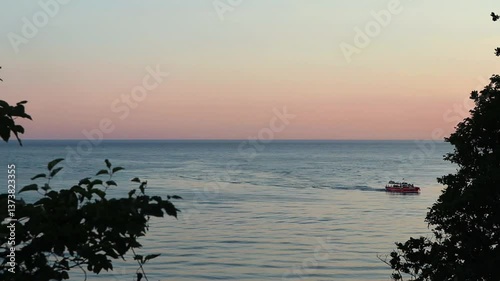 Beautiful, summer, warm sunset on the shores of the Black Sea. Vacation, recreation, tourism. A tourist boat floats in the distance. High quality FullHD footage