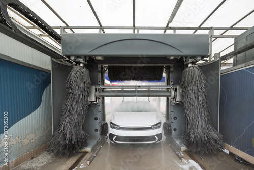 Automatic car wash cleaning white car with rotating brushes
