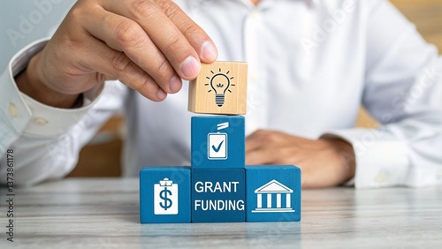 Man holding colorful blocks with icons and inscription: GRANT FUNDING. Concept of grants and fund