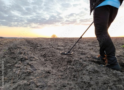 Man with a metal detector in a field in the evening. Metal detecting field. Copy space