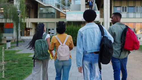 Rear view of young group of American student friends walking around university campus going to college classes. Education and back to school concept.