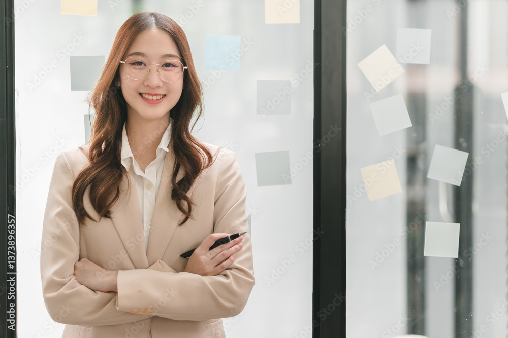 Professional woman smiling in office with sticky notes on glass wall emphasizes success and collaboration Professional woman smiling in office with sticky notes on glass wall emphasizes success and collaboration