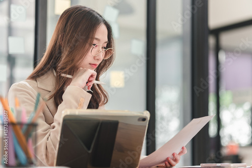 Young professional analyzes documents while working in modern office environment for improved productivity
