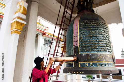 Travelers thai women hit knell ancient big metal bell in antique belltower belfry for respect blessing holy buddha travel visit worship at Wat Kalayanamit Temple on March 9, 2025 in Bangkok, Thailand