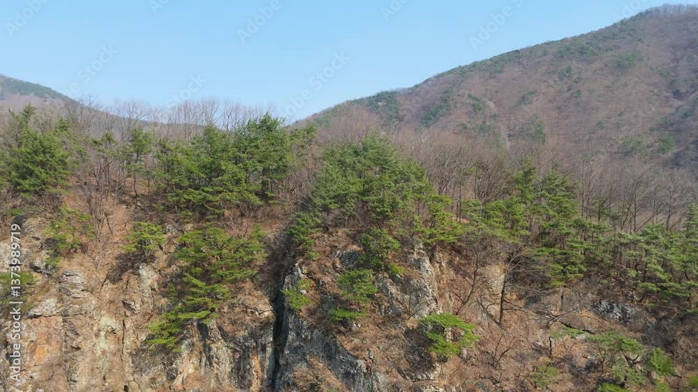 A view of Mungyeong's Clean Valley filmed by drones. A view of a cold winter valley with ice frozen by a stream and fallen leaves A view of Mungyeong's Clean Valley filmed by drones. A view of a cold winter valley with ice frozen by a stream and fallen leaves