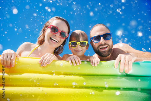 Happy family playing in waterpark. People having fun on summer vacation. Family jumping into swimming pool with splashes of water.