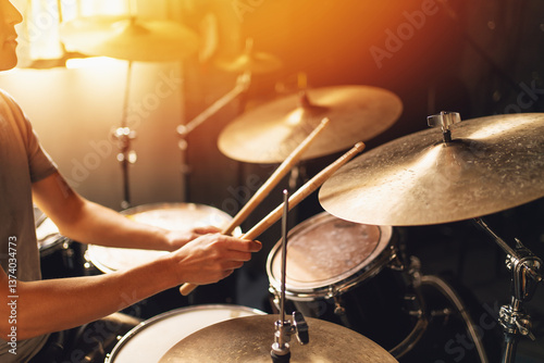 Drummer playing drum set in bright home studio with sunlight, concept of music performance, rhythm, percussion, musician lifestyle and sound production. photo