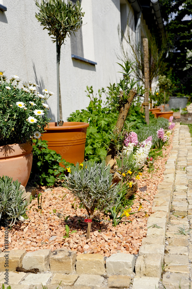 Naklejka premium Blumenbeet mit Sandstein Würfel Pflasterstein Einfassung, Rasen