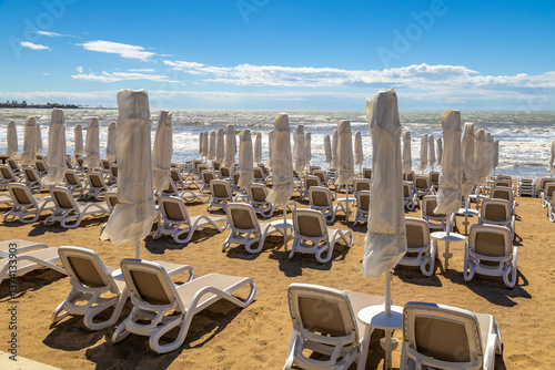 Fototapeta Naklejka Na Ścianę i Meble -  Early spring in Side: empty beach with perfectly aligned sunbeds and parasols awaits tourists. Peaceful pre-season tranquility on Mediterranean coast.   Antalya province, Turkey	