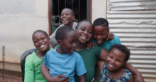 Poverty. Inequality. Portrait of a happy smiling black African woman and her children sitting in front of their shack in a township in Africa
