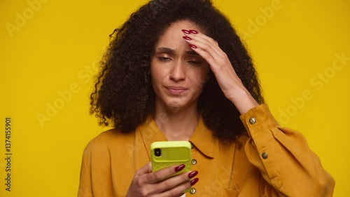 Upset Woman Reacting to Bad News on Phone on Yellow Background photo