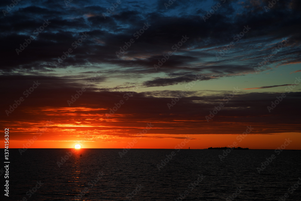 Obraz premium sunrise or sunset over the sea with brightly colorful clouds in the blue sky
