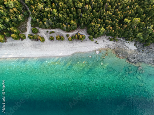 Aerial 90 degree straight down photo of emerald crystal clear water, rocky shore overgrown with green boreal forest. Bruce Peninsula, Georgian Bay, Ontario, Canada. 