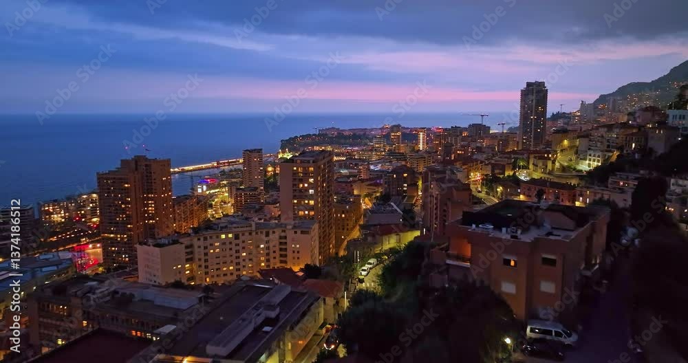 Aerial establishing shot of illuminated city buildings. Aerial view of illuminated skyscraper in residential city at night, Monte Carlo, Monaco Aerial establishing shot of illuminated city buildings. Aerial view of illuminated skyscraper in residential city at night, Monte Carlo, Monaco
