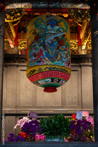 Obraz na płótnie An ornate painted lantern hangs in a temple above a beautiful floral offering in Taipei. w salonie
