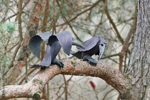 Fake metal bird imitation to repeal real birds. Metal artistic statue on the tree.