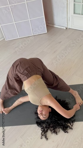 Brunette woman doing gymnastics yoga asana vertical