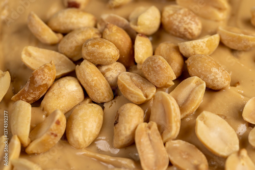 peanut butter on a piece of bread and roasted peanuts on the table