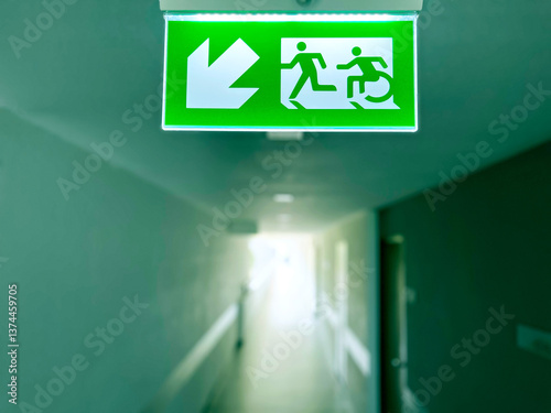 emergency exit sign, Emergency exit sign with wheelchair accessibility symbol in a modern building corridor. Safety evacuation route for people with disabilities