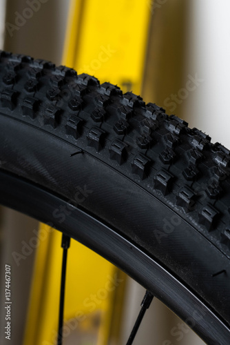 Close up bicycle tire on yellow bike rack in workshop.