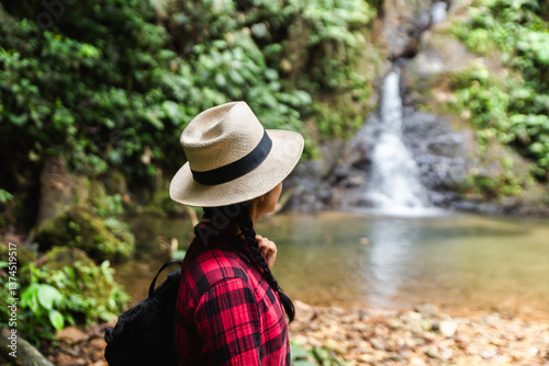 Woman in hat viewing waterfall in Ecuadorian rainforest