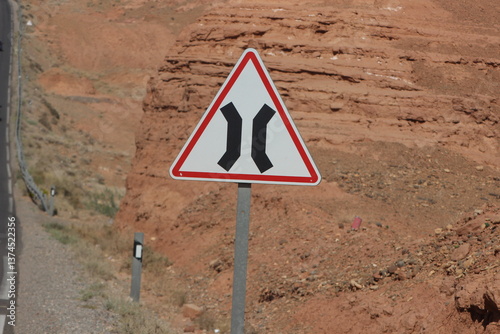 A close-up of a narrow road traffic sign