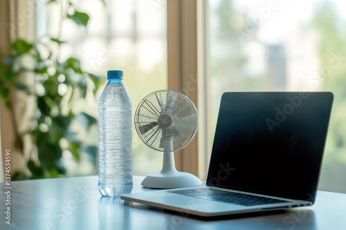Cold water and a small fan cooling a home office desk in summer, with a laptop and a plant in the background