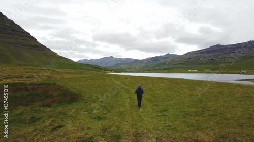 Man with a spirit of adventure walks through the grass toward the famous Icelandic mountain Kirkjufell in western Iceland. 4K video.