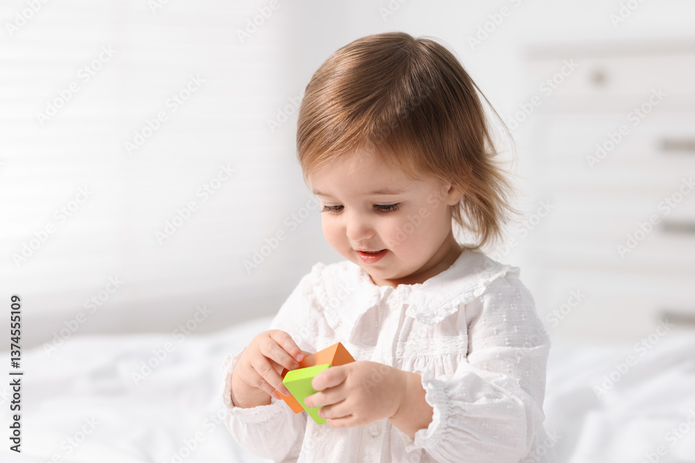 Cute little baby girl playing with toy on bed at home Cute little baby girl playing with toy on bed at home