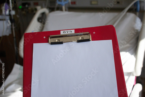 CLIP BOARD ROJO CON HOJAS PARA REPORTE MEDICO EN HABITACIÓN DE HOSPITAL