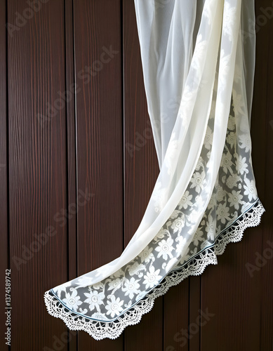 White sheer curtain with floral patterns draping over wooden surface