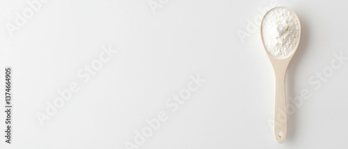 Flat lay of a wooden spoon with a handle. the spoon is filled with a white powdery substance, which appears to be flour or sugar.