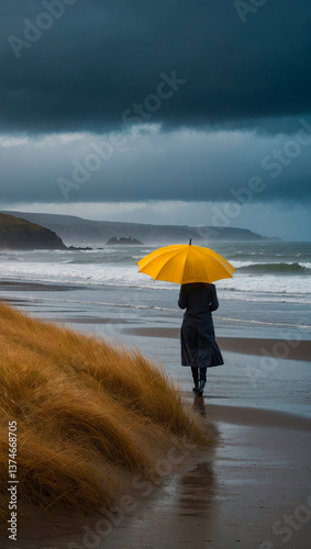 Woman with yellow umbrella walking on beach under storm clouds