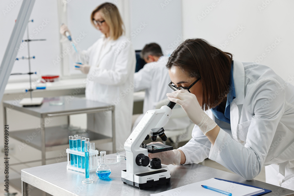 Scientist working with microscope at table in laboratory Scientist working with microscope at table in laboratory