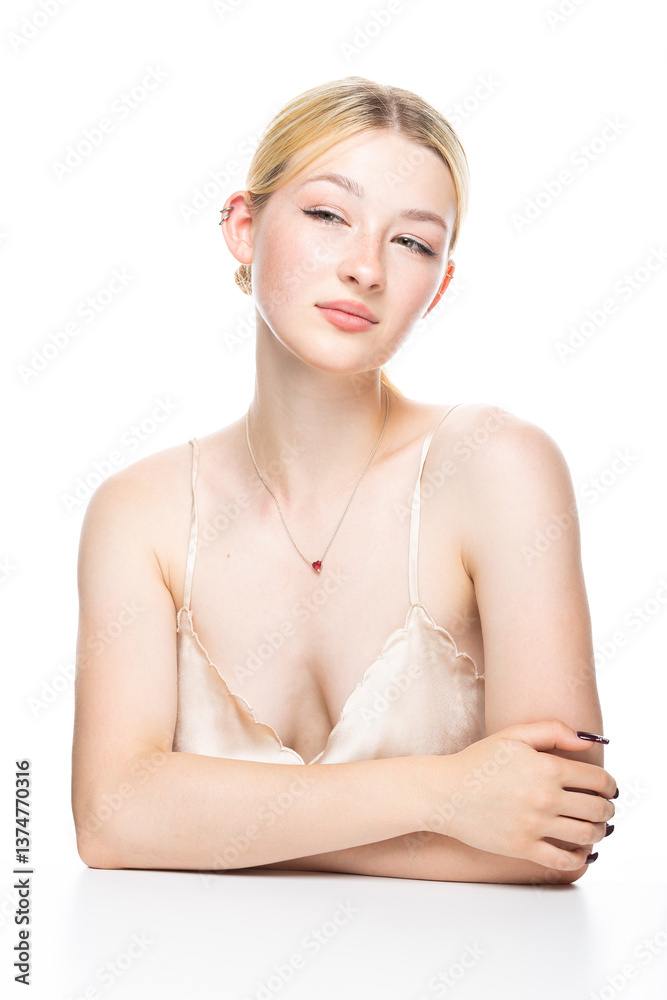 Obraz premium A young blonde girl with freckles in a golden top. Beauty portrait of a woman on a white background in the studio.