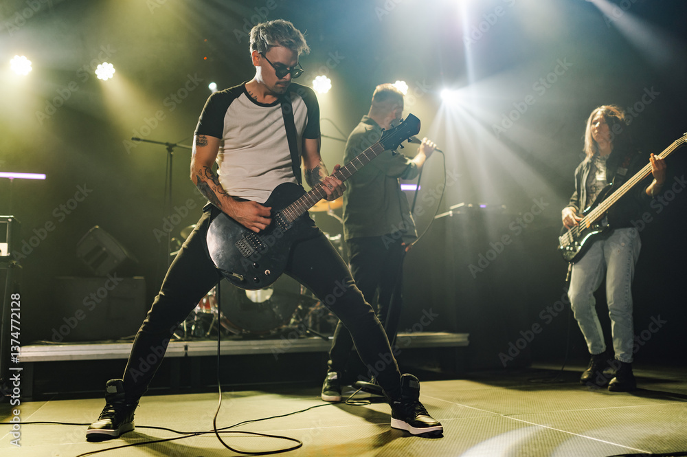 Fototapeta premium Guitarist performing with band on stage during music concert