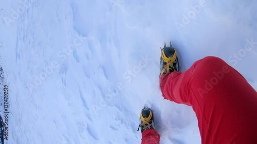 A close-up shot of a climber's foot in a crampon ascending a snowy slope, highlighting the determination and effort required in mountaineering.