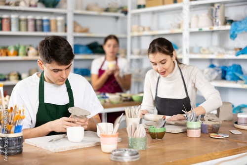 Young woman and young man sculpting ceramic product in workshop