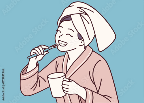 Asian woman in pink pajamas brushing her teeth while holding a white mug, with a towel wrapped on her head, smiling in front of a solid blue background, showing fun morning hygiene routine