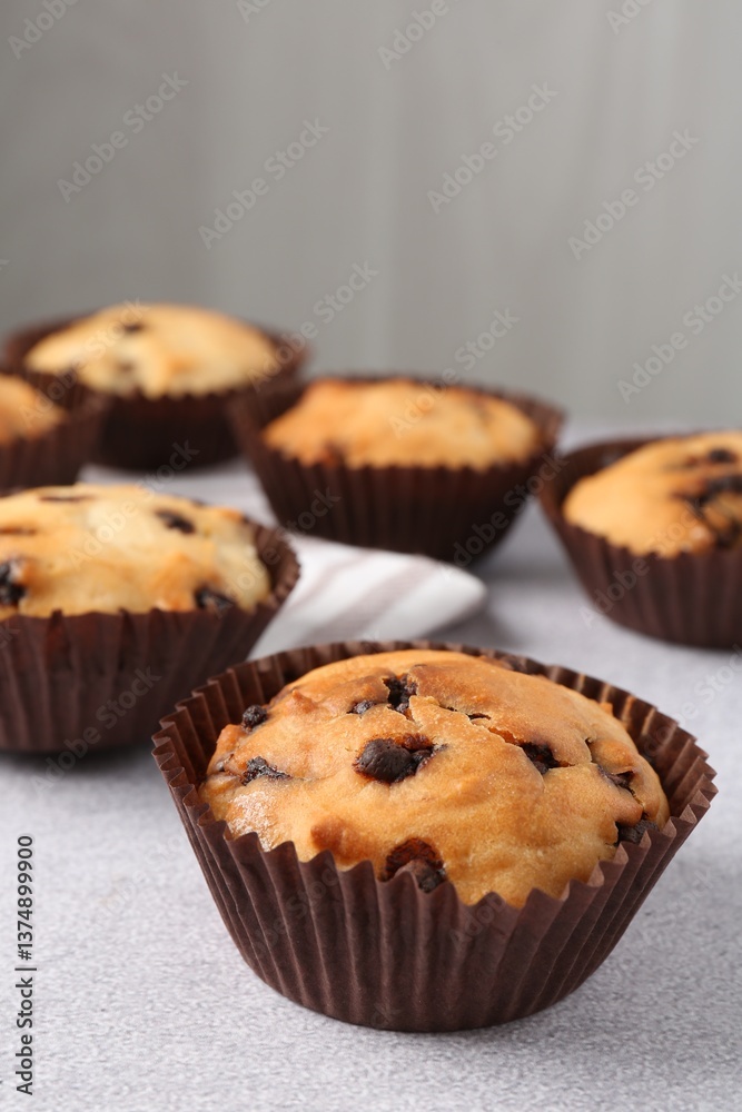 Delicious muffin with chocolate chips on light grey table, closeup Delicious muffin with chocolate chips on light grey table, closeup