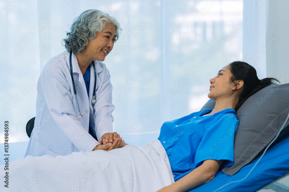Obraz premium An elderly Asian female doctor is writing on a clipboard with a young female patient in a hospital room.