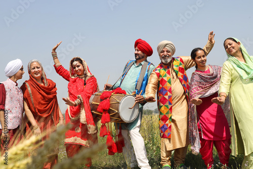 Punjab people celebrating Baisakhi or vaisakhi festival in agriculture field and doing bhangra dance. Punjabi sikh family enjoying festive season together, Culture of india.