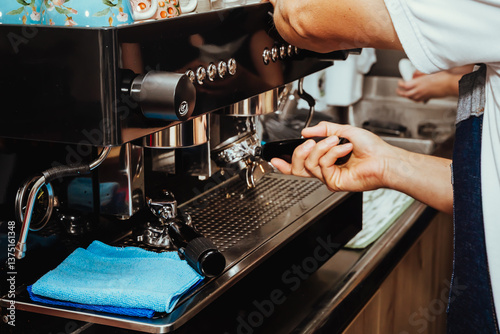 Photo barista cleaning filter of espresso machine to prepare coffee, with Colombian cups on it, lancet to texturize the milk and cleaning cloths in a Colombian coffee shop.