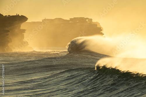 Large waves crash along Sydney’s rocky coastline at sunrise.
