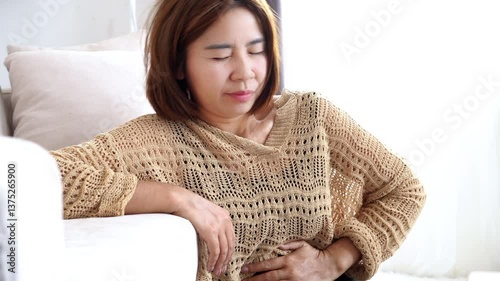 asian woman abdominal cramps and diarrhea, hand holding stomachache possibly due to gastroenteritis, helicobacter  pylori infection, or other digestive system issues
