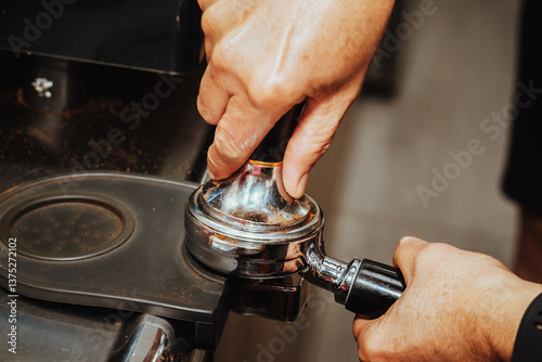 photo of barista's hands pressing with tamper the ground coffee in the filter of an espresso machine in a Colombian coffee shop. photo