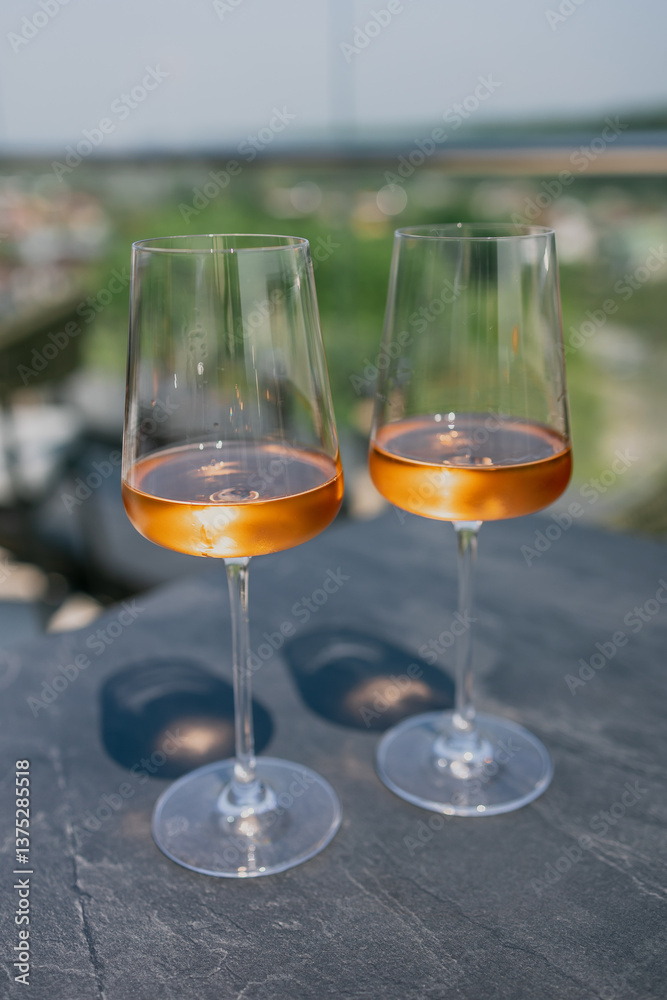 Obraz premium Two glasses of rose wine on a sunlit outdoor table