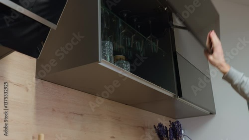 Wallpaper Mural Man opens upper kitchen cabinet and takes drinking glass. Hand opens cupboard with transparent glasses Torontodigital.ca