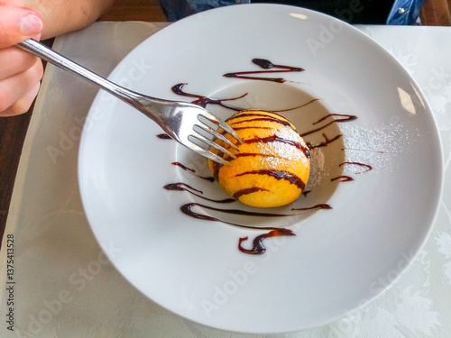 Close up of a fork sticking into a fried ice cream dessert in a dish. Flat lay, top view. Typical Chinese cake.